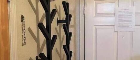 A room with a white door, a coat rack with multiple hooks, and a small piece of paper on the door.