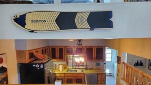 Eine Küche mit Holzausstattung, einem schwarzen Kühlschrank und einer Pendelleuchte.