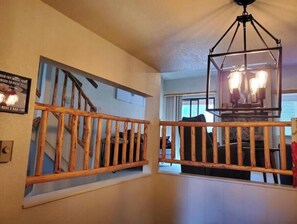 A staircase with a wooden railing, a hanging light fixture, and a wall-mounted sign.
