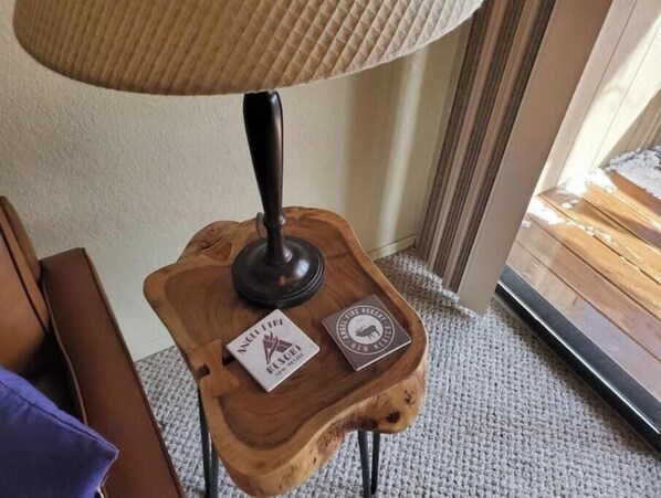 A wooden side table with a lamp and two plaques.