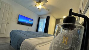 Ein Schlafzimmer mit Bett, Deckenventilator, Fernseher an der Wand und einer besonderen Lampe.