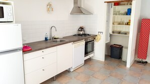 A kitchen with white cabinets, a stainless steel sink, a stove, and a microwave. - Cottage (sleeps 4) at Domaine de Chantageasse, a 17th century estate with pool (Asnières-la-Giraud)