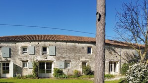 A stone building with a tiled roof, multiple windows with shutters, and a well-maintained lawn. - Cottage (sleeps 4) at Domaine de Chantageasse, a 17th century estate with pool (Asnières-la-Giraud)
