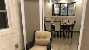 Un espace patio aménagé avec des meubles en osier, une table en verre et un coin repas comprenant des chaises et une table.