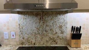 Une cuisine équipée d’une hotte en acier inoxydable, d’une plaque de cuisson à induction noire et d’un plan de travail en granit.