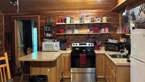 Una cocina tipo cabaña de madera con una isla central, estufa, refrigerador y ventilador de techo.