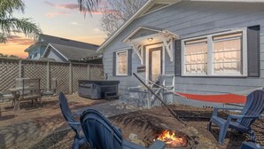 A house with a fire pit in the backyard, outdoor seating, and a covered patio area.