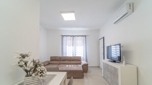 A modern living room with a beige sofa, a flat-screen TV, and a white cabinet. - Relax Flatroom 22 (Olbia)