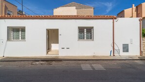 A white building with a tiled roof, a door, and two windows with metal bars. - Relax Flatroom 22 (Olbia)