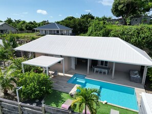Une maison dotée d’un patio couvert, d’une piscine et d’un jardin.