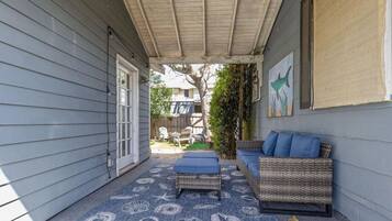 A covered patio with wicker furniture and a blue patterned rug.