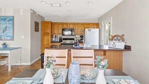 Une cuisine moderne avec des meubles en bois, un îlot central et un coin repas avec une table dressée pour deux personnes.