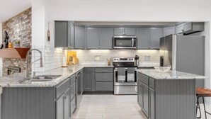 Una cucina moderna con mobili grigi, un forno in acciaio inossidabile e un microonde.
