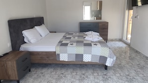 Une chambre à coucher avec un lit, une table de chevet, une commode, un miroir et une fenêtre.