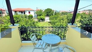 Un balcon avec une table ronde et deux chaises, entouré d’une rambarde en métal.