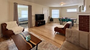 Una sala de estar con televisión, sofá y mesa de comedor.
