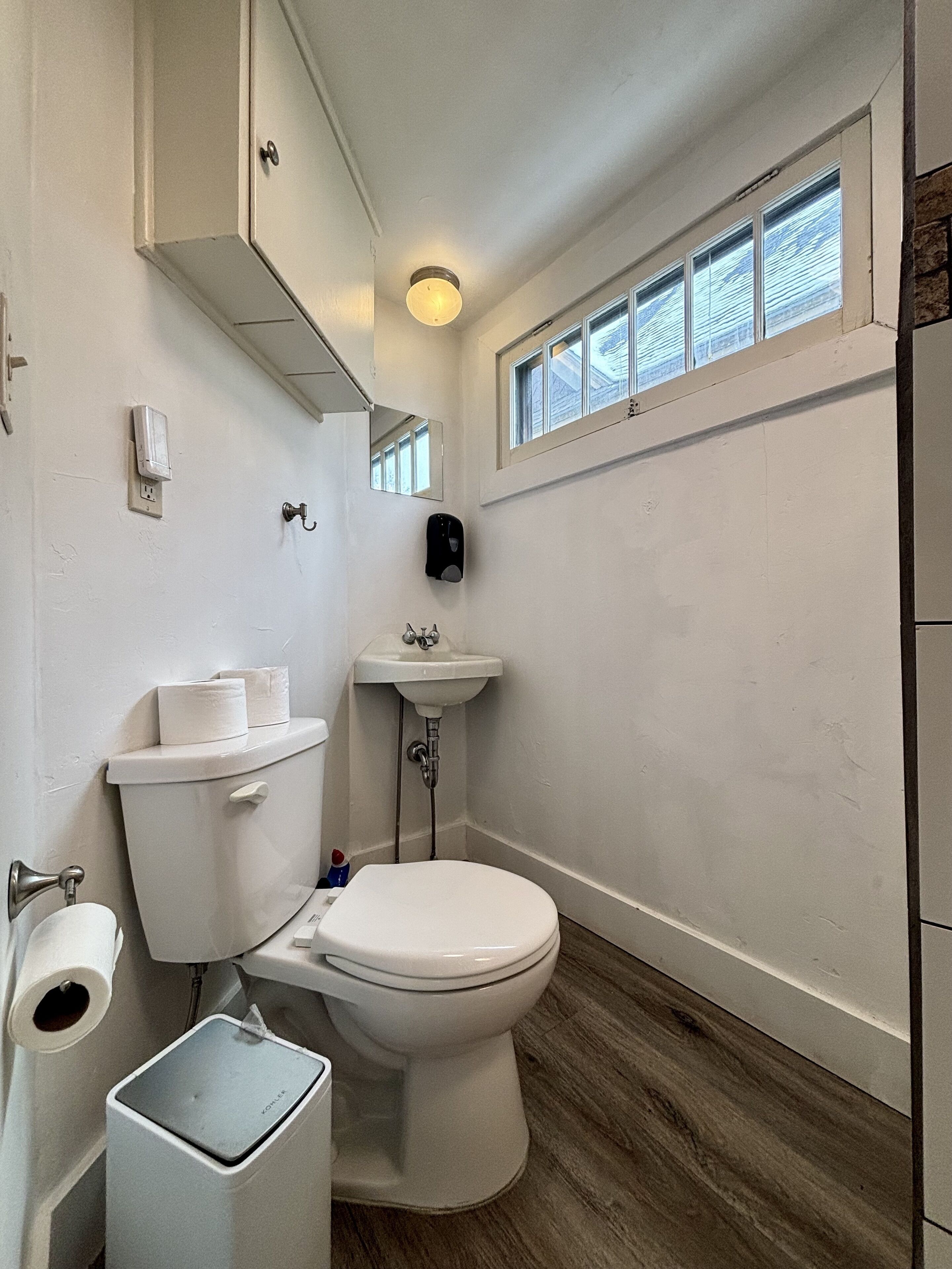 A compact bathroom with a toilet, sink, and a small trash bin.