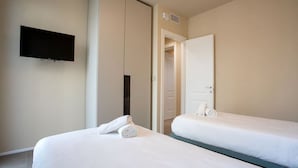 Une chambre d’hôtel avec deux lits simples, un téléviseur à écran plat fixé au mur et une porte donnant accès à une salle de bain.