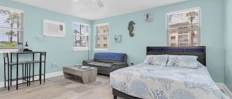 A bedroom with a bed, a desk, a chair, a sofa, and a ceiling fan.
