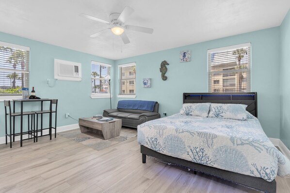 A bedroom with a bed, a desk, a chair, a sofa, and a ceiling fan.