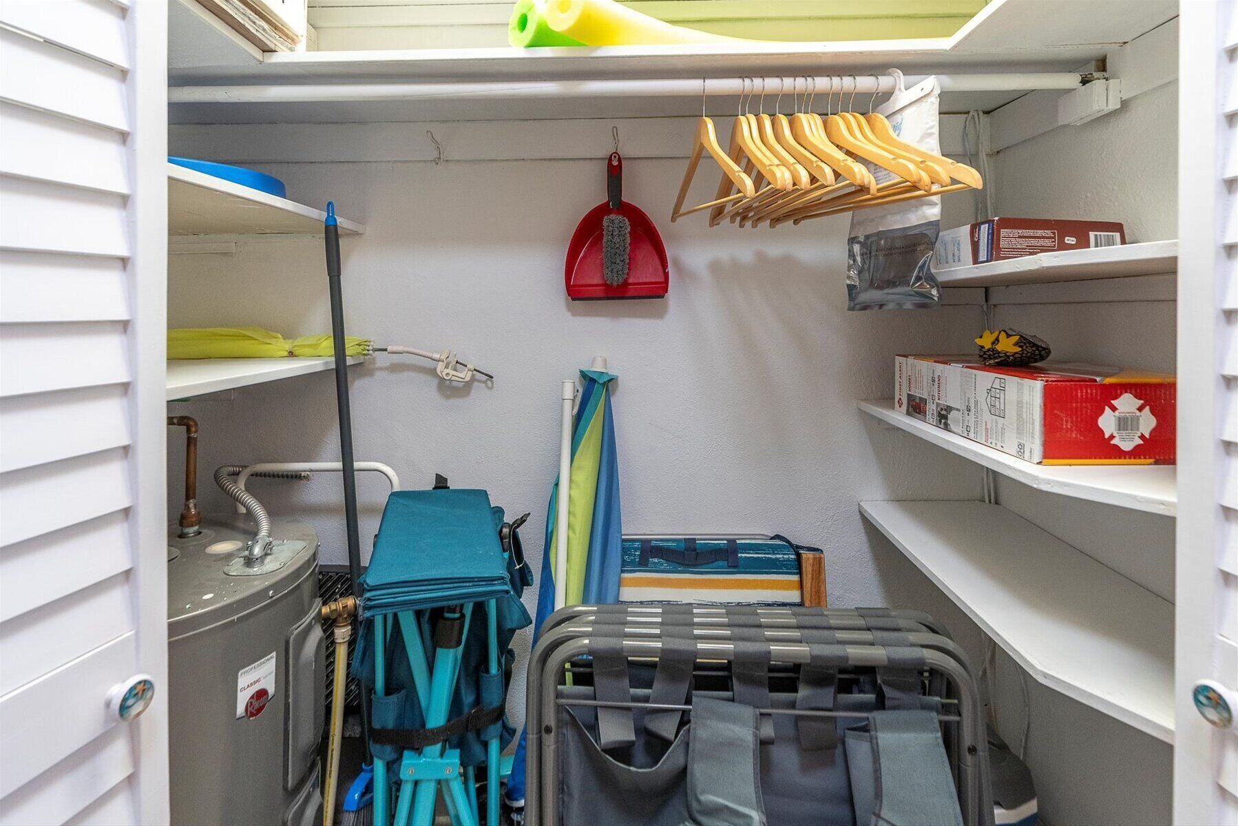 Een kleine opbergruimte met planken, een bezem, een veger en schoonmaakmiddelen.