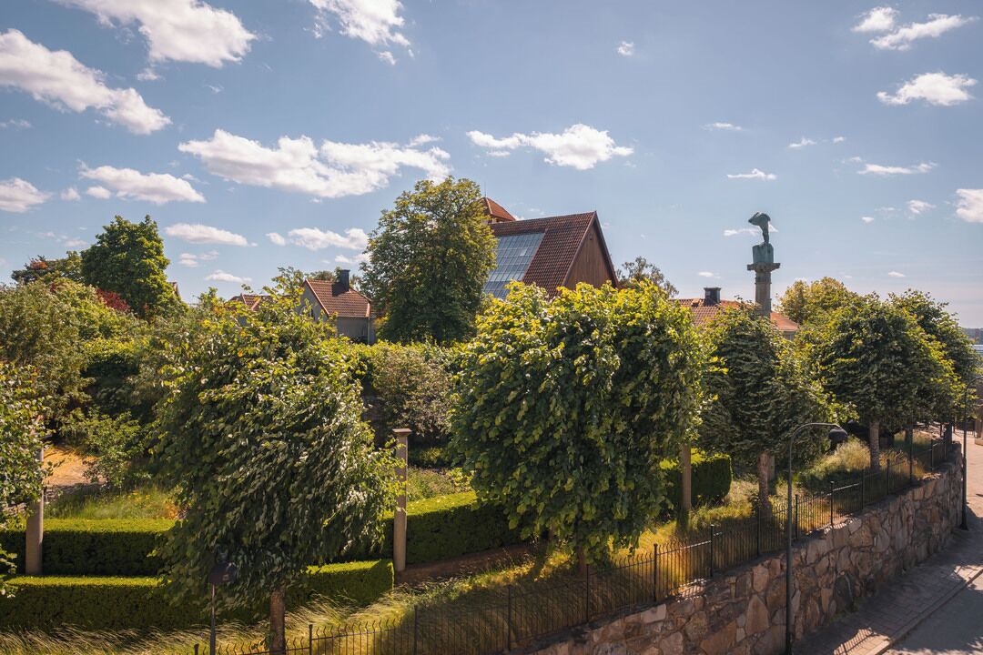 A residential area with houses, a stone wall, and a statue.