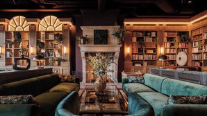 A cozy library with green sofas, a fireplace, and bookshelves filled with books. - Villa Foresta (Lidingo)