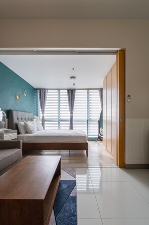 Une chambre moderne avec un grand lit, une table basse en bois et une vue sur l’extérieur grâce à de grandes fenêtres.