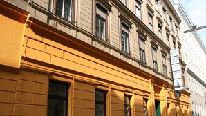 A building with a yellow facade, multiple windows, and a sign indicating it is a hotel. - Hotel Admiral (Vienna)