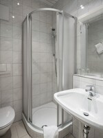 Casa de banho moderna com chuveiro em cabine de vidro, lavatório branco e sanita.