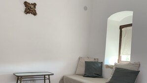A room with a sofa, a small table, and patterned floor tiles. - Casa Talia Houses (Modica)