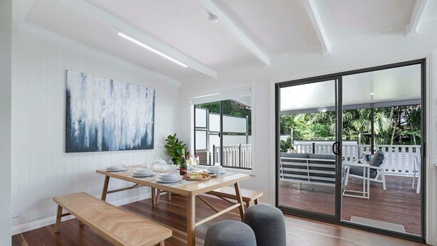 A dining area with a wooden table set for four, benches, and grey ottomans. - Sunset Haven 4-Bd Retreat Milton, Steps to Stadium (Petrie Terrace)