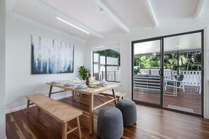 A dining area with a wooden table set for four, benches, and grey ottomans. - Sunset Haven 4-Bd Retreat Milton, Steps to Stadium (Petrie Terrace)