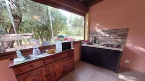 Cozinha com armários de madeira, fogão a gás e janela com vista para o verde.