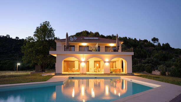 Ein modernes, zweistöckiges Haus mit Schwimmbecken davor.