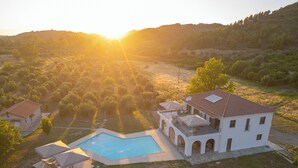 Ein großes Haus mit Swimmingpool, eingebettet in eine hügelige Landschaft.