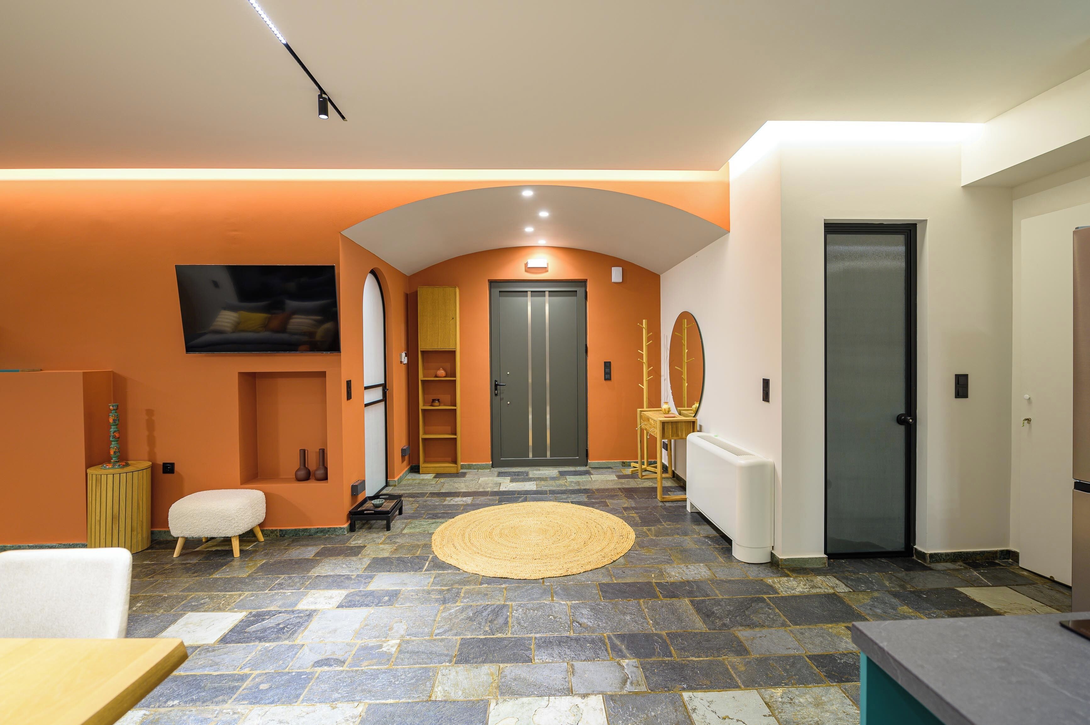 A modern interior with a stone floor, a round rug, a white sofa, and a door with a glass panel.