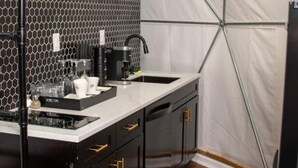 Een moderne keuken met een wit aanrecht, zwarte kastjes met gouden handgrepen en een backsplash met een honingraatpatroon.
