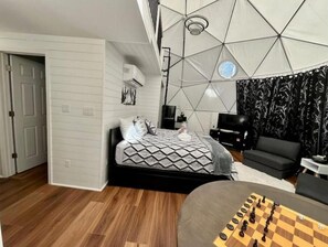 A modern bedroom with a geometric ceiling, a bed with patterned bedding, a TV, and a chessboard on the floor. - Contrast Cove Dome in Smoky Mountains - GlampiTiN

 (Hartford)