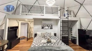 Ruime tentkamer met een bed, een klein tafeltje en een balkon.