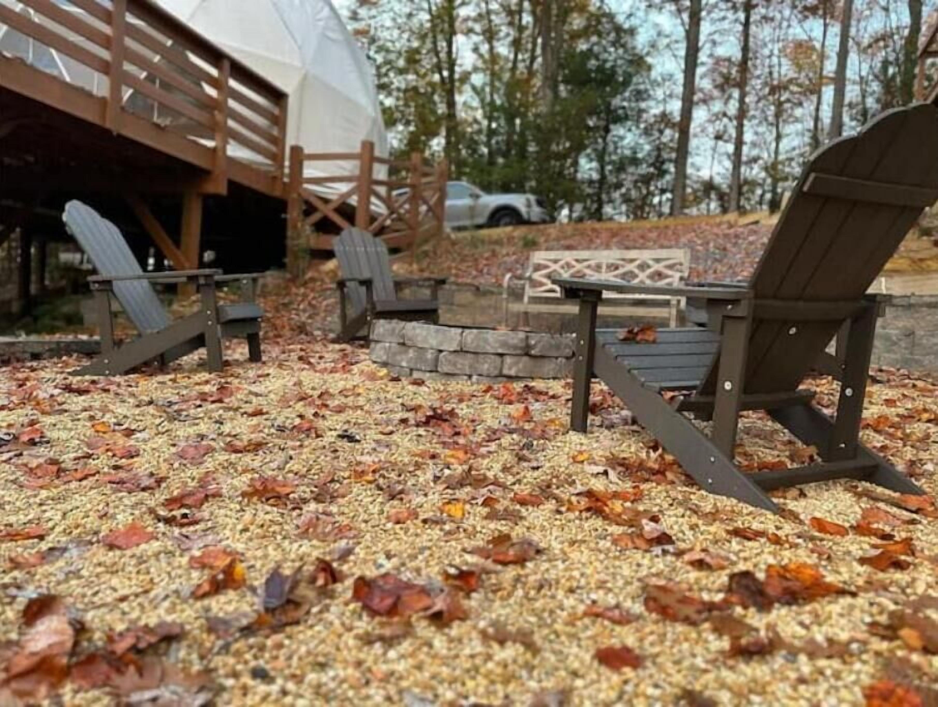 A covered outdoor seating area with Adirondack chairs and a stone fire pit.