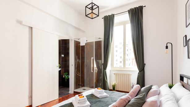 Moderni hotellihuone, jossa on sänky, suihku ja näkymä kaupunkiin.