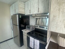 A compact kitchen with a refrigerator, toaster, oven, and microwave.