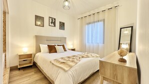 Un dormitorio ordenado con una cama grande, mesitas de noche, un espejo y obras de arte en la pared.