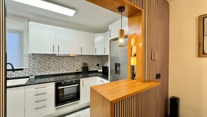 Una cocina moderna con armarios blancos, encimera negra y una isla de madera.