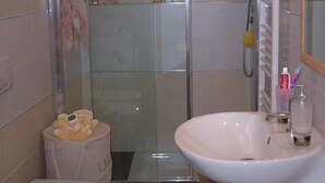 Un bagno con cabina doccia in vetro, un water e un lavandino con specchio.