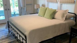 Une chambre à coucher avec un lit, un ventilateur de plafond, une fenêtre avec des rideaux et une vue sur l’extérieur.