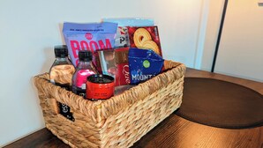 Una cesta de mimbre con diversos alimentos y una piruleta helada sobre una mesa de madera.