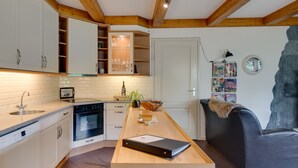 A modern kitchen with white cabinets, a central island, and a black leather sofa.