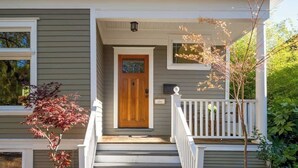 A two-story house with a front porch, a wooden door, and a small window above the door. - Paradise Haven-95 walk score-Dedicated Workspaces (Portland)